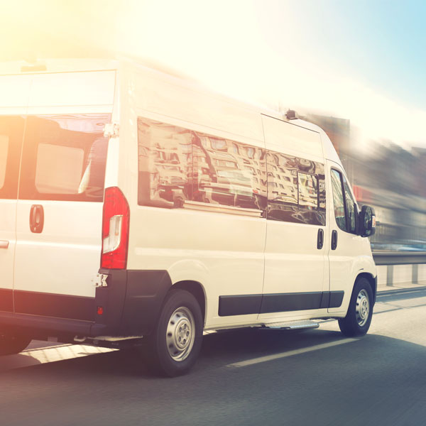 Unrecognizable small passenger van hurry up on highway at city s