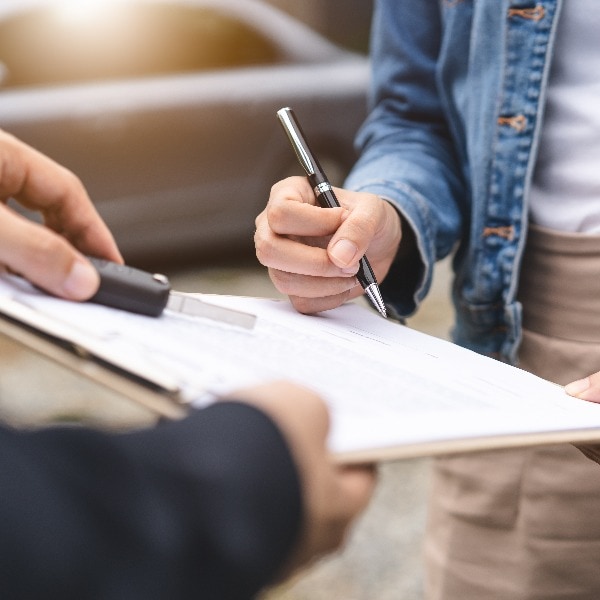 Concept car rental service. Close up view hands of agent giving car key to client that rent a vehicle in rental office.