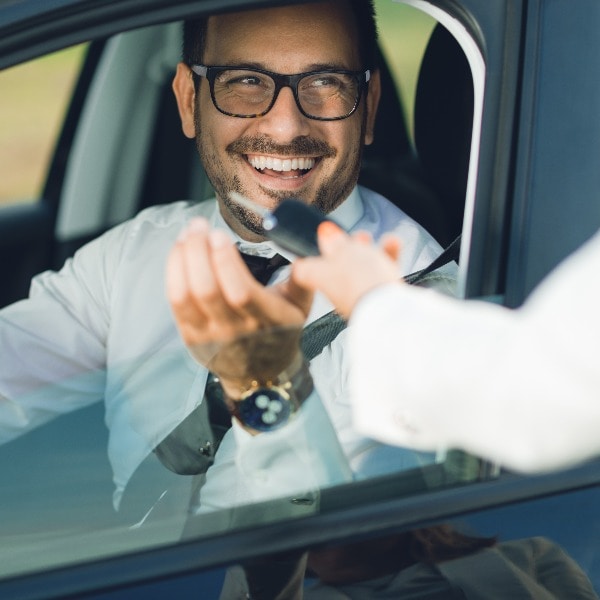 Happy businessman taking the car keys from unrecognizable person